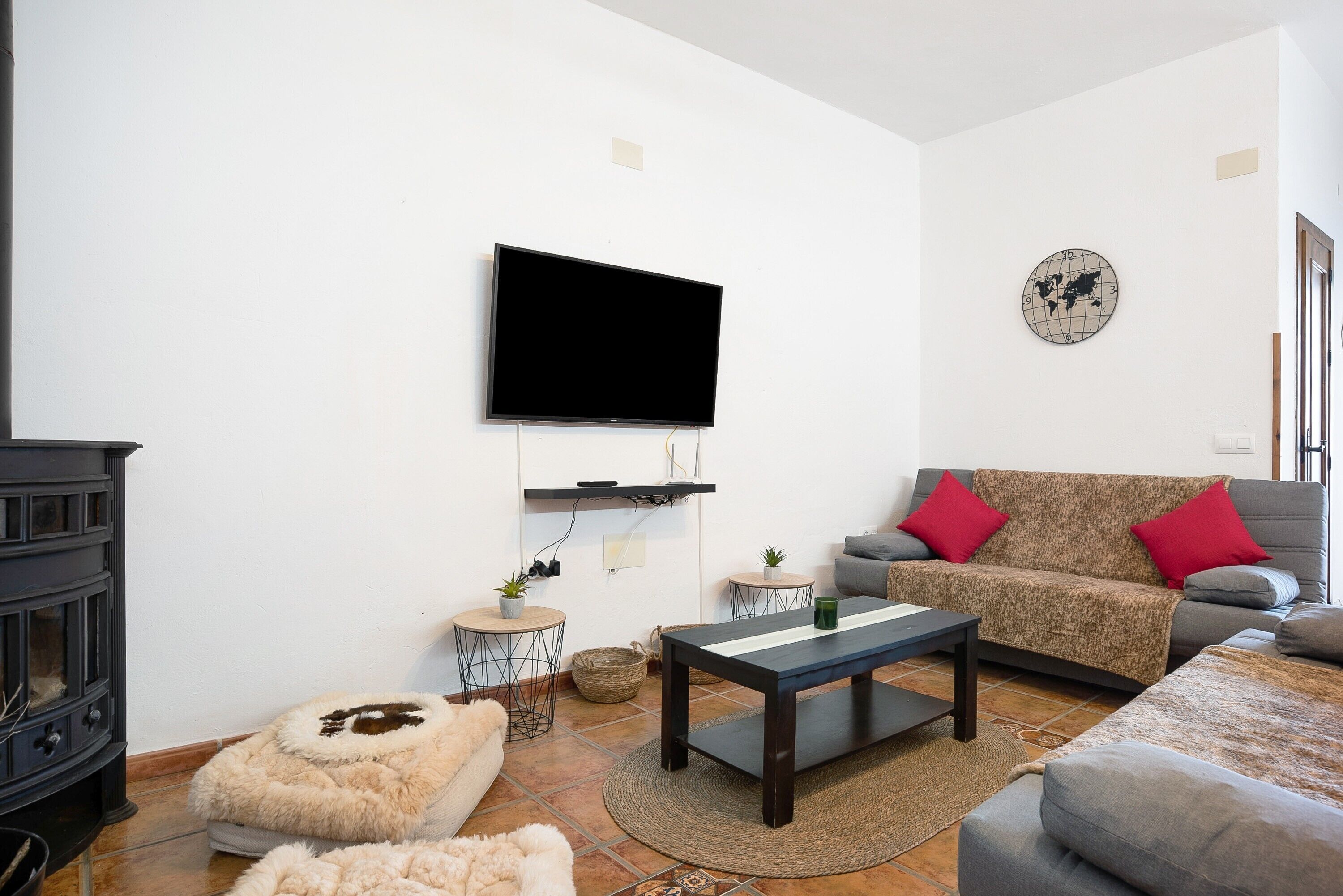Una sala de estar con televisor de pantalla plana, un sofá, una mesa de centro y una chimenea.