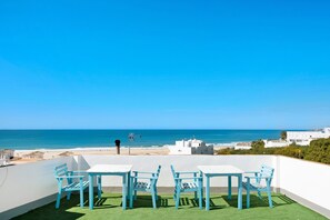 Una terraza con vista al mar, paredes blancas y sillas azules.