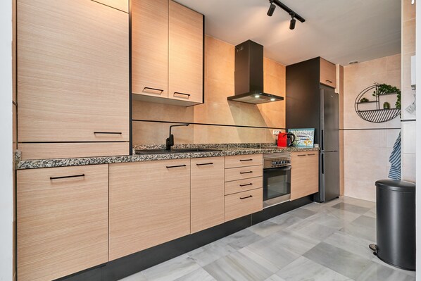 A modern kitchen with wooden cabinets, a stainless steel refrigerator, and a granite countertop. - '2-Bedroom Apartment with Seaview', Wi-Fi and Air Conditioning (Nerja)
