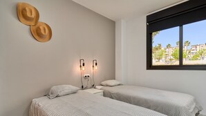 A room with two beds, a window with a view, and two wall-mounted light fixtures. - '2-Bedroom Apartment with Seaview', Wi-Fi and Air Conditioning (Nerja)