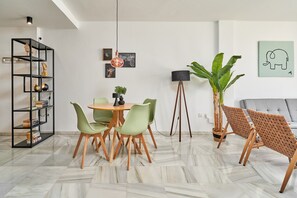 En moderne stue med spiseplads, en gulvlampe og en stor plante.