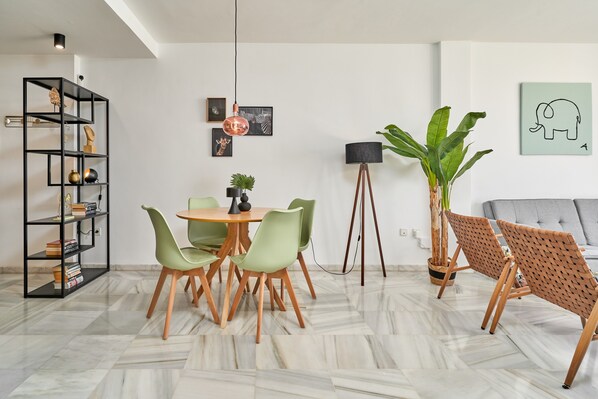 Ein modernes Wohnzimmer mit Essbereich, einer Stehlampe und einer großen Pflanze.