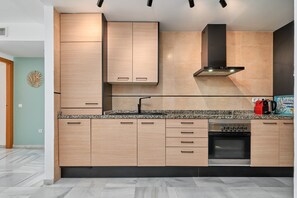 Eine moderne Küche mit Holzausstattung, einem Edelstahlbackofen und einer schwarzen Dunstabzugshaube.