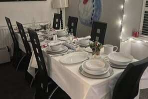 A dining table set with white tablecloths, plates, and cutlery, surrounded by black chairs. - Rural Chapel Cottage, Near Airport, bar & hot tub (Aberdeen)