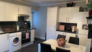 A compact kitchen with a washing machine, a microwave, and a bread box. - Rural Chapel Cottage, Near Airport, bar & hot tub (Aberdeen)