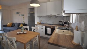 A modern kitchen with white cabinets, a wooden dining table, and a large pendant light.