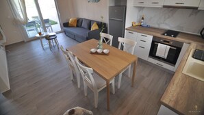 A modern kitchen with white cabinets, a wooden dining table, and a refrigerator.