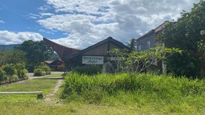 Un chalet rustique, agrémenté d’une enseigne bien visible indiquant « RANTEPAO Lodge », se dresse au milieu d’une végétation luxuriante, sous un ciel dégagé.