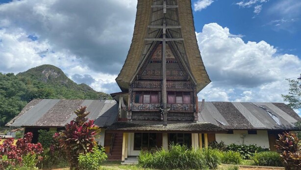 Un bâtiment traditionnel doté d’un toit en pente, en forme de pyramide, et d’une tour centrale.