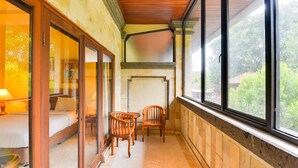 A covered balcony with wooden flooring, a sofa, two chairs, and a table. - Super OYO Townhouse Oak Maxi Hotel Legian (Kuta)