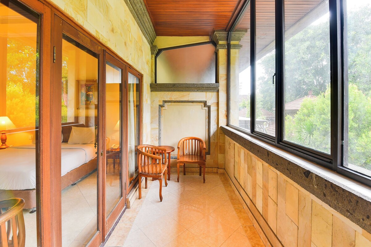 Ein überdachter Balkon mit Holzboden, einer Couch, zwei Stühlen und einem Tisch.