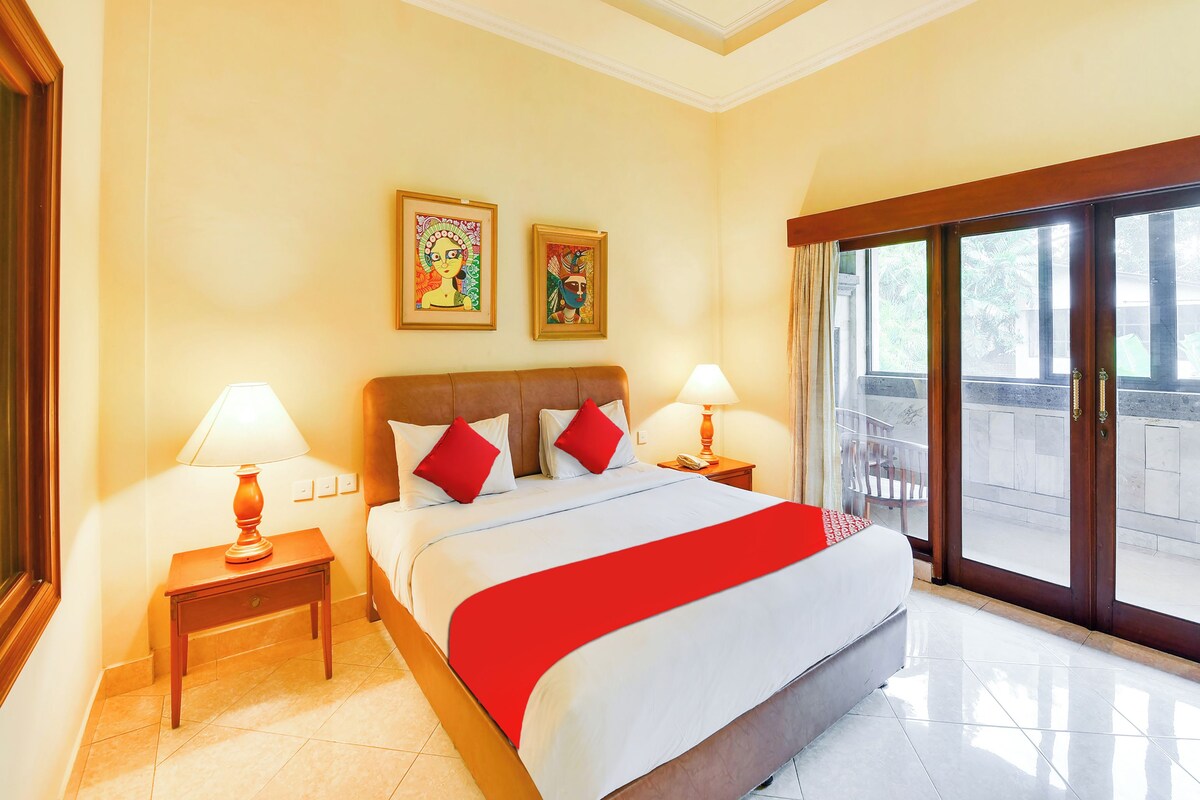 A hotel room with a large bed, two nightstands, a window with a view, and artwork on the wall.