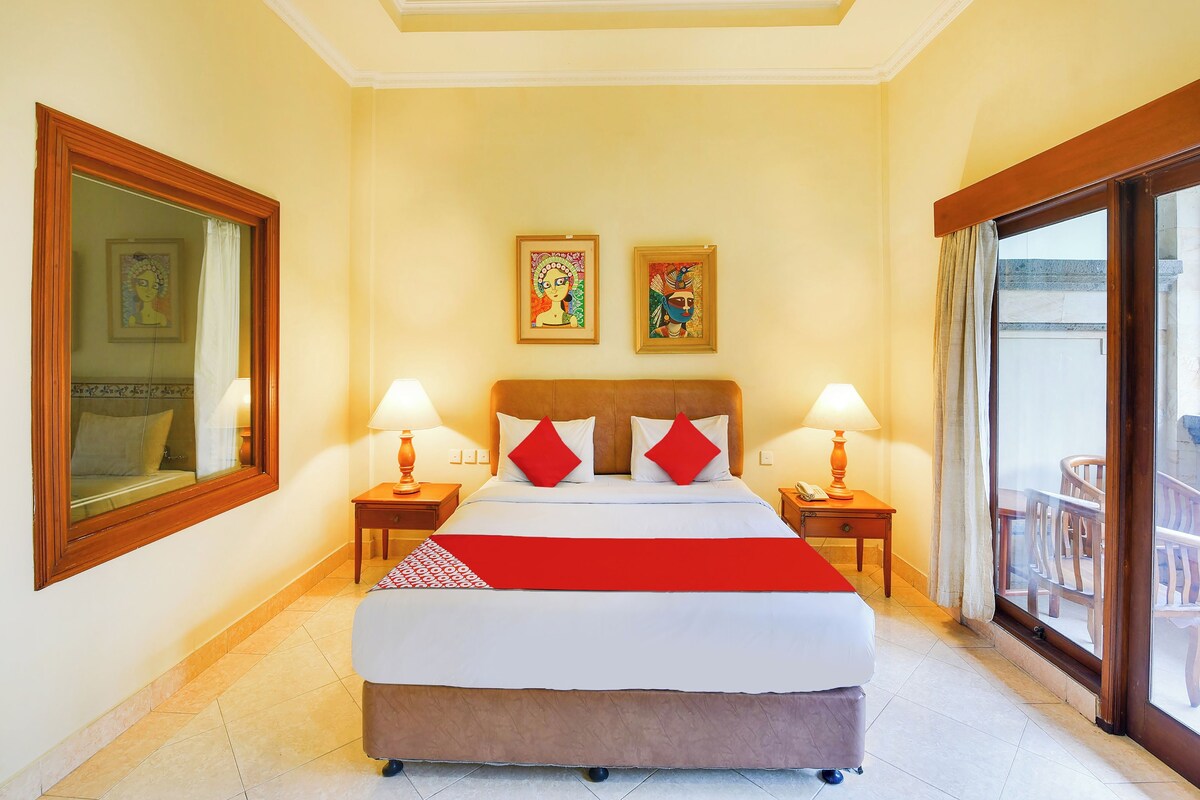 Ein Hotelzimmer mit einem großen Bett, zwei Nachttischlampen, einer roten und weißen Bettdecke sowie Bildern an den Wänden.