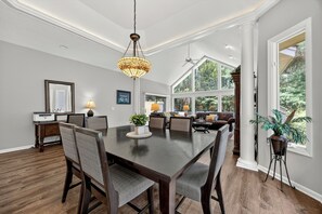 A dining area with a dark wooden table, grey upholstered chairs, and a hanging light fixture.