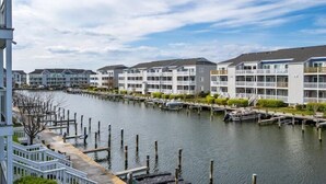 A waterfront hotel with multiple-story buildings, docked boats, and a wooden walkway along the water.