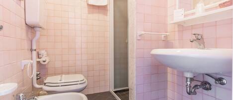 Un baño con inodoro, bidé, lavabo y zona de ducha.