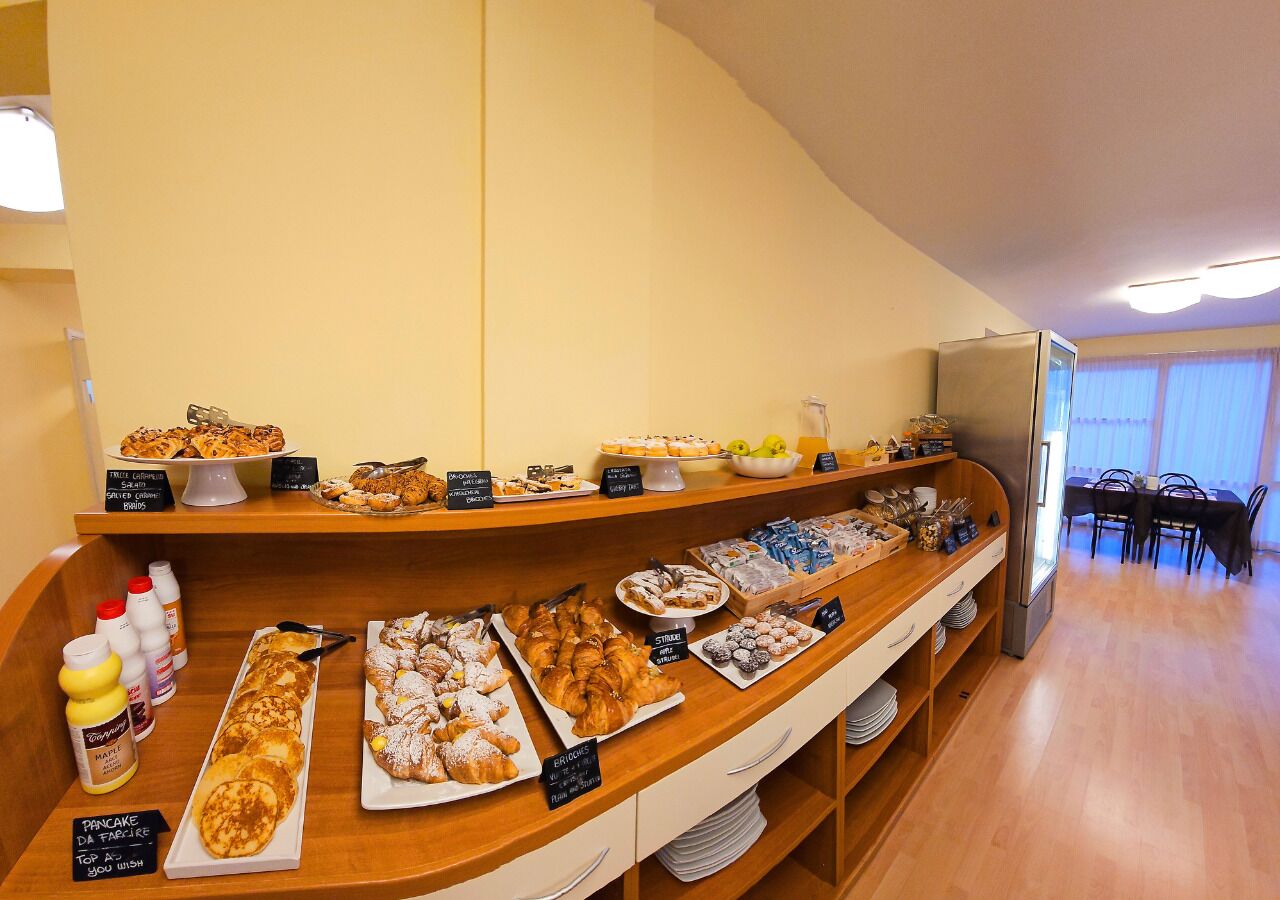 A buffet area with various food items and a dining area in the background.