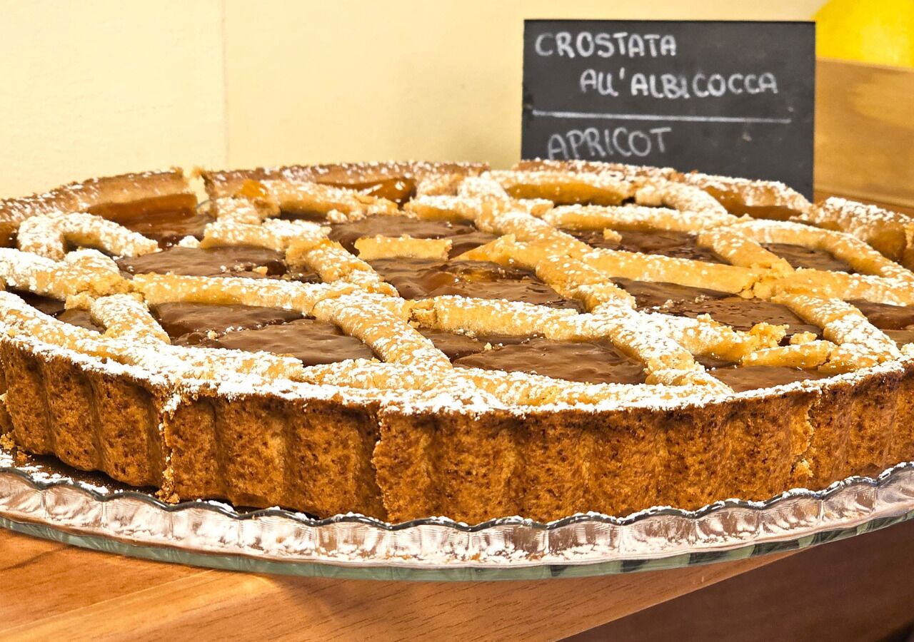 Un pastel redondo con cobertura enrejada sobre un plato de vidrio.