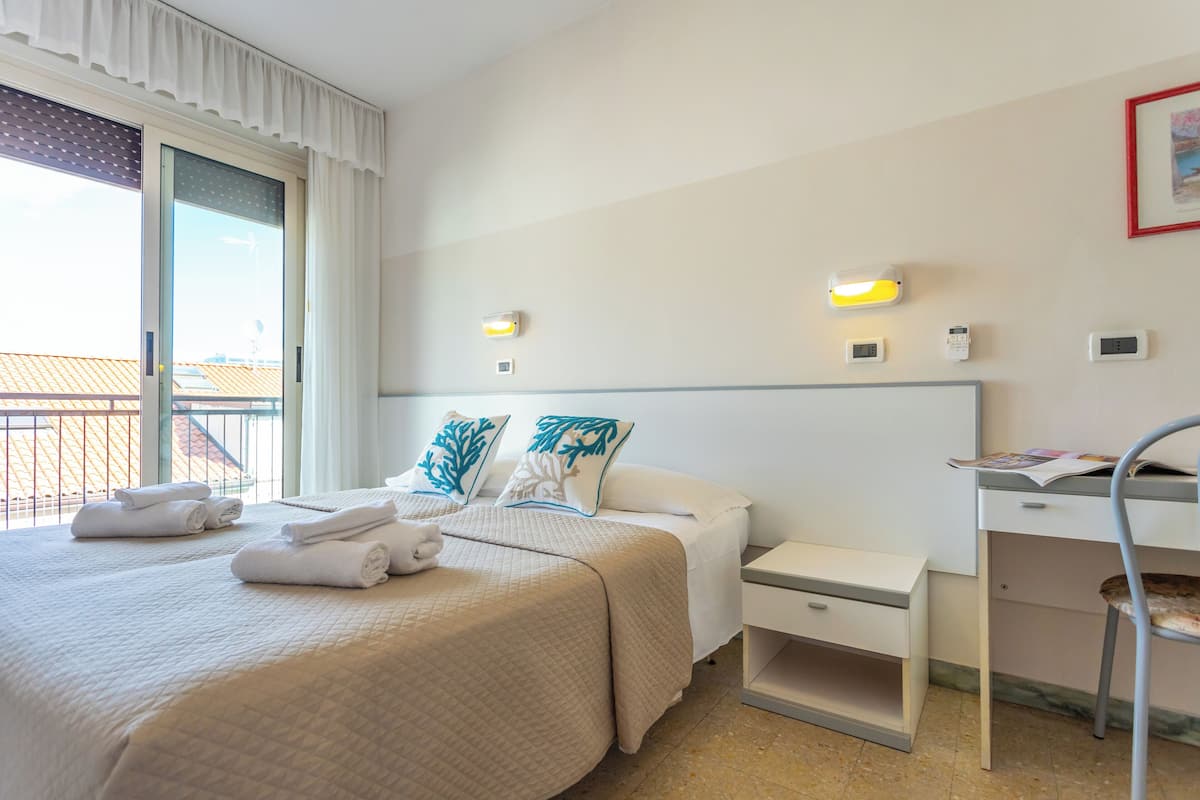A hotel room with a bed, two bedside tables, a desk, and a chair.