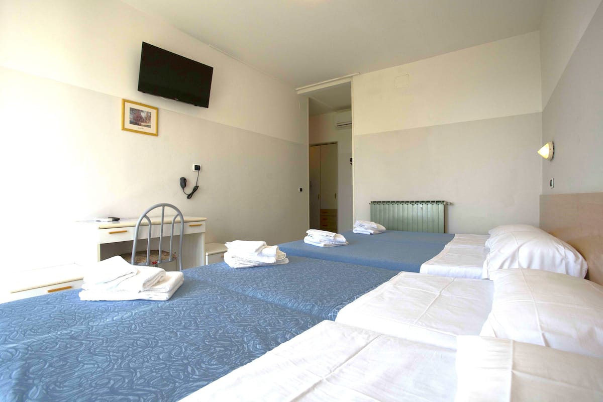 A hotel room with two beds, a desk, a chair, a telephone, and a television mounted on the wall.