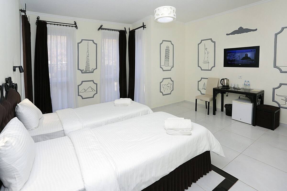 A hotel room with a large bed, a desk, a chair, and a television.