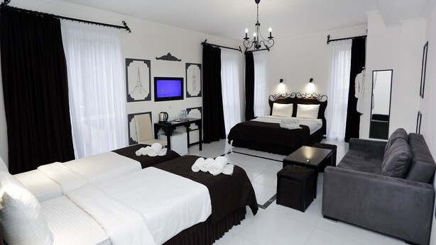 Une chambre d’hôtel moderne équipée de deux lits, d’un canapé, d’un bureau et d’une télévision.
