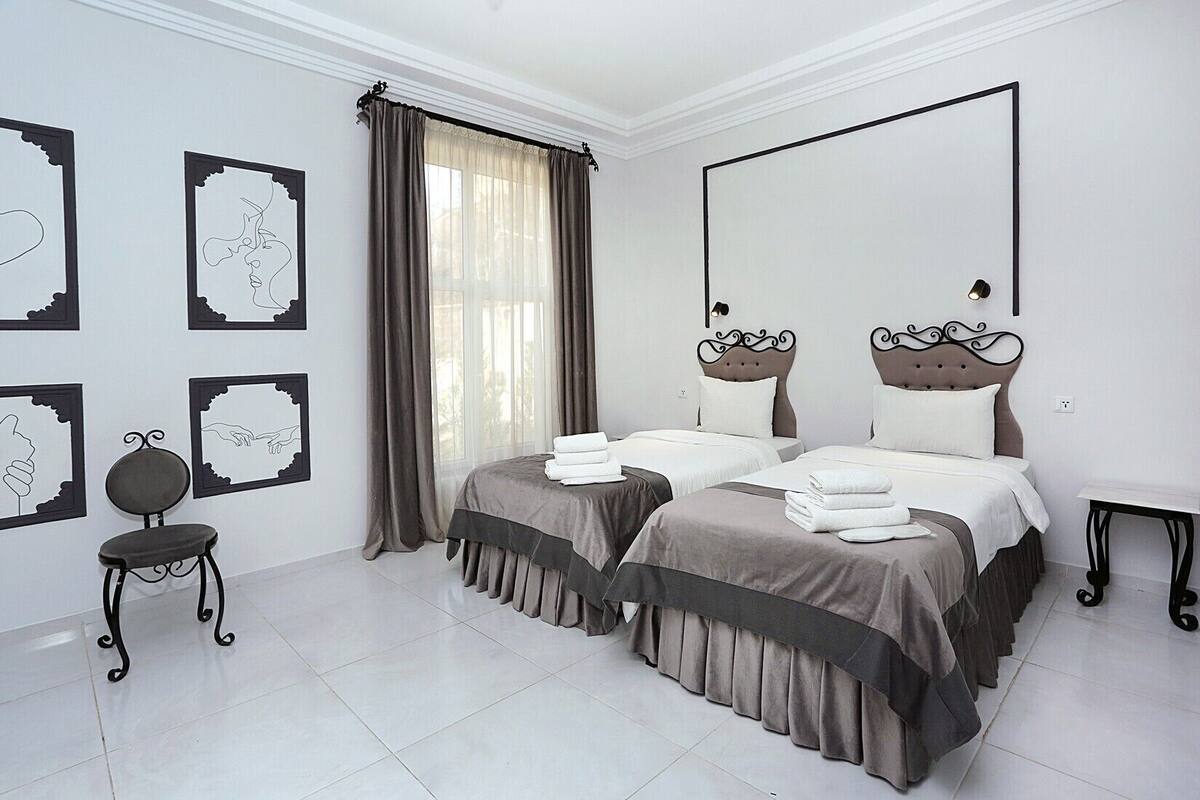 A hotel room with two beds, a chair, and artwork on the walls.