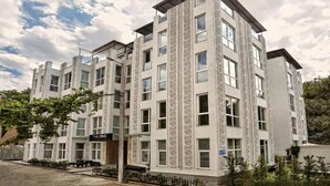 Un immeuble à plusieurs étages, doté d’un style architectural moderne, caractérisé par une colonne verticale imposante et une enseigne portant l’inscription « THE ONE ».
