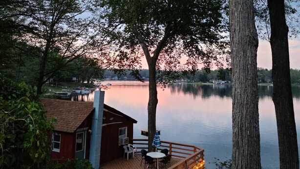 En hytte ved søen med terrasse, udendørs siddepladser og udsigt over søen.