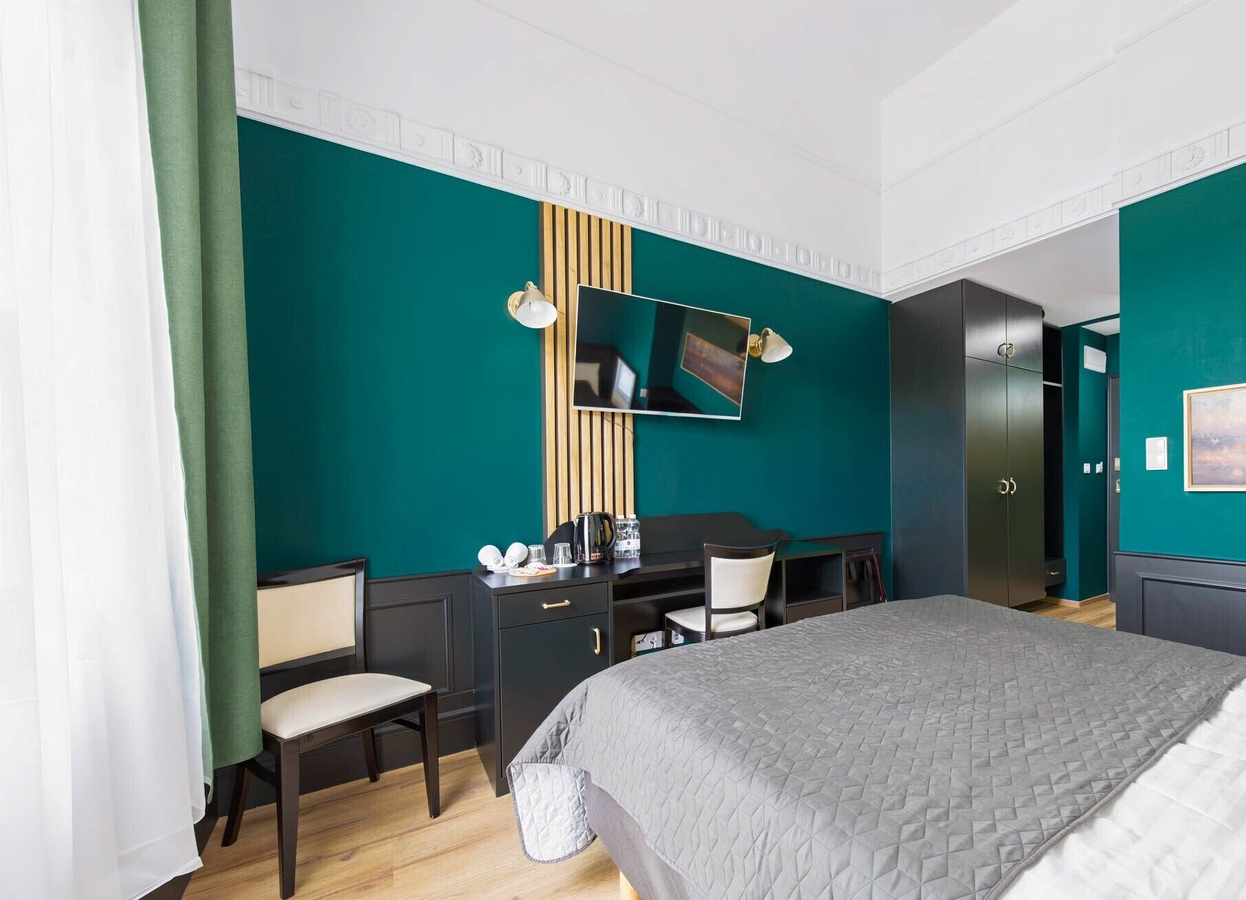 A hotel room with a bed, desk, chair, and wardrobe.