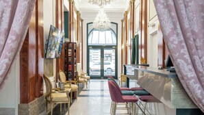 A hotel lobby with a grand chandelier, a reception desk, and a seating area with chairs and sofas. - Hotel Praga 1885 (Prague)