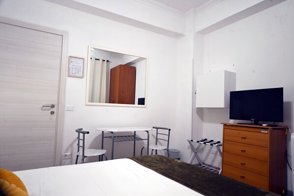 A bedroom with a bed, a dresser, a TV, a desk with chairs, and a mirror. - Appia Antica Guest House (Rome)
