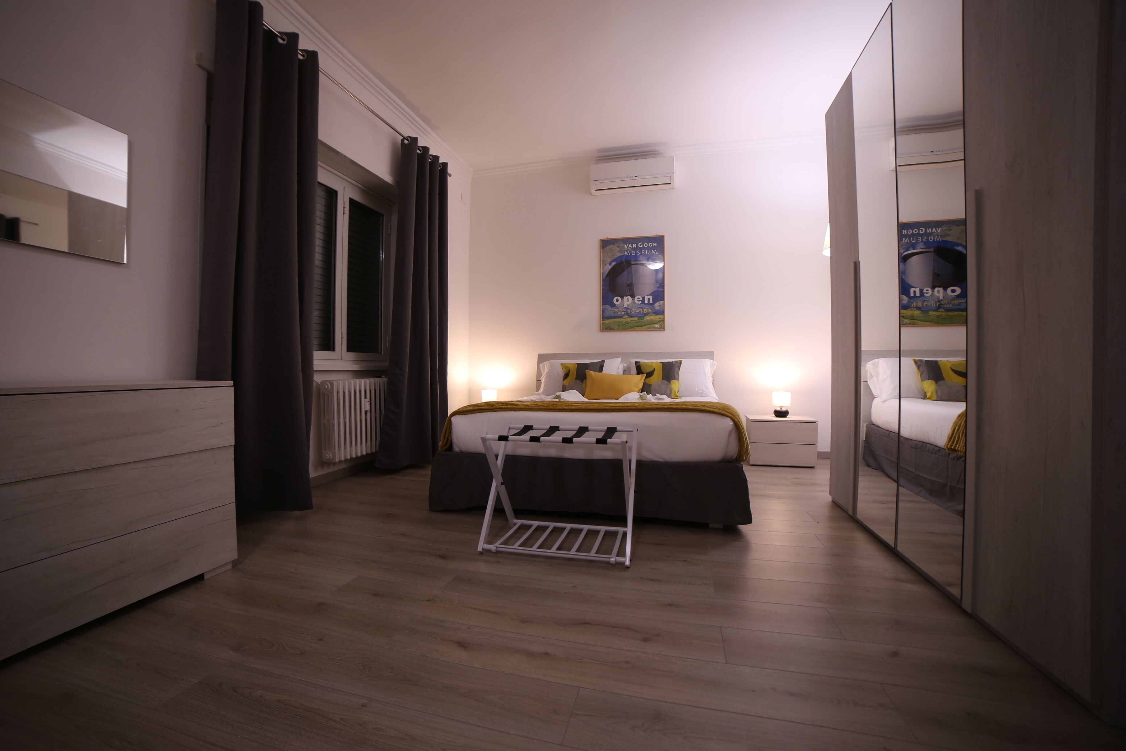 A modern bedroom with a bed, bedside table, and a mirror.