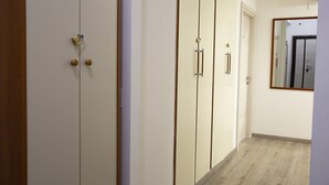 A hallway with a wooden floor and white walls. There are three doors with handles and a small mirror on the wall. - Appia Antica Guest House (Rome)