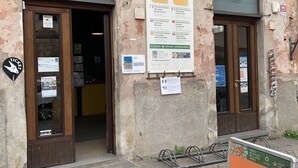 An old building with two wooden doors, a signboard for bike rental, and a metal bike rack. - Appia Antica Guest House (Rome)