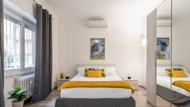 A modern bedroom with a large bed, a bedside table, a mirror, and a window with curtains. - Appia Antica Guest House (Rome)