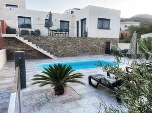 Une maison moderne dotée d’une piscine, d’un escalier en pierre et de mobilier d’extérieur.