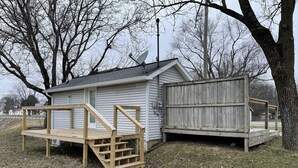 A small wooden shed with a wooden deck and a fenced area.