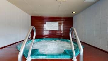 Un bain à remous doté de barrières métalliques, entouré de murs carrelés et de panneaux en bois.
