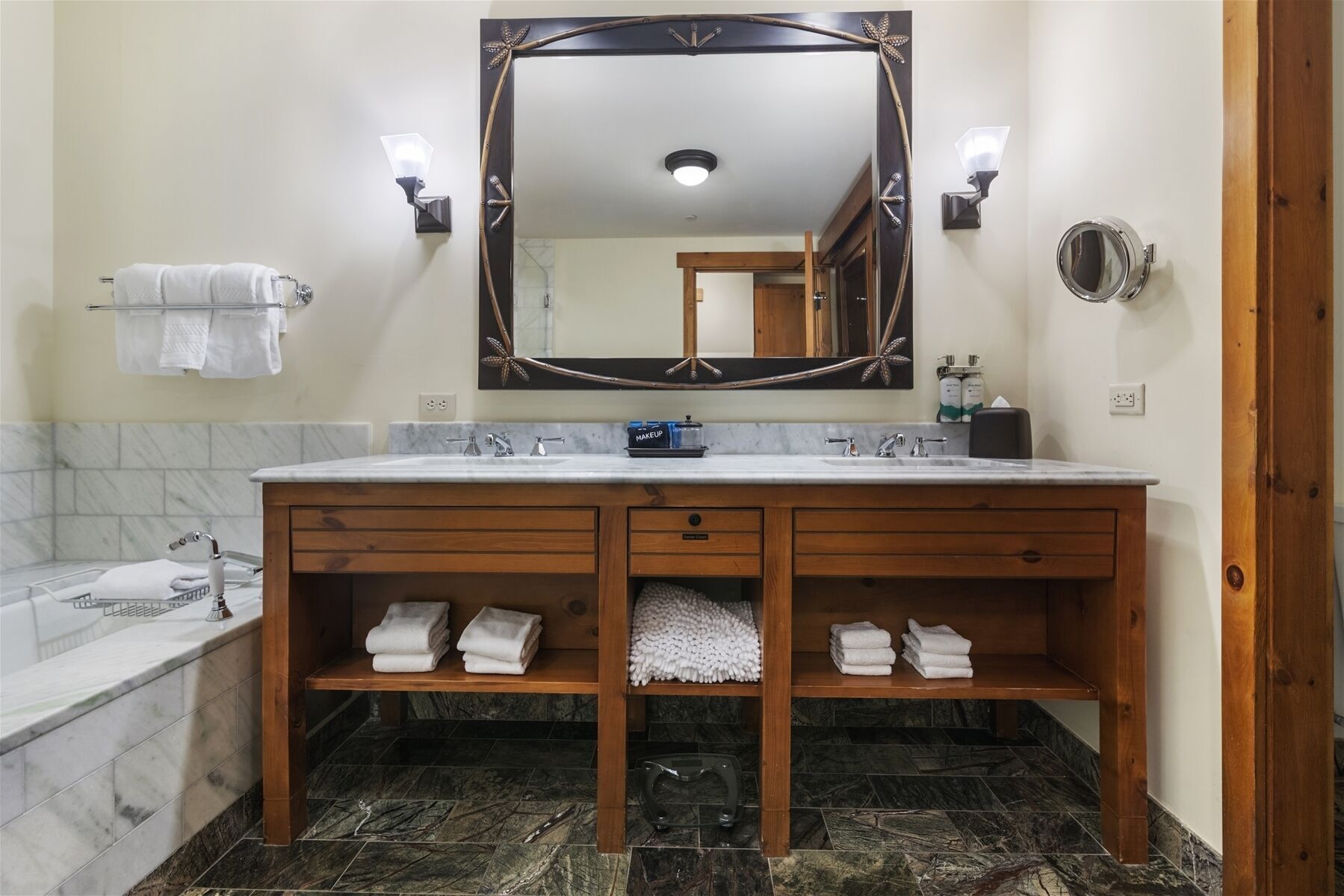Une salle de bain avec un lavabo en marbre, un meuble-lavabo en bois et un grand miroir.
