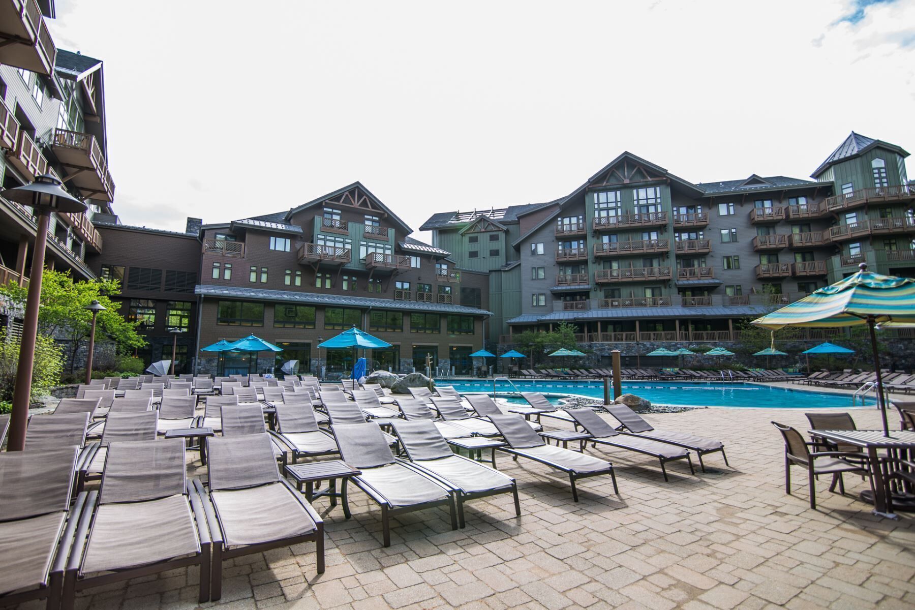 A resort with a swimming pool, lounge chairs, and umbrellas.