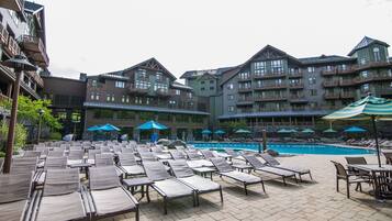 A resort with a swimming pool, lounge chairs, and umbrellas.