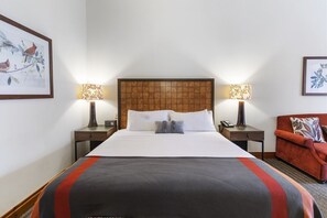 A hotel room with a large bed, two bedside tables with lamps, a red armchair, and framed artwork on the walls. - Ski in/out! Large Studio in Lodge at Spruce Peak (Stowe)
