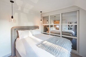Camera da letto moderna con un letto grande, un armadio a muro e illuminazione a sospensione.