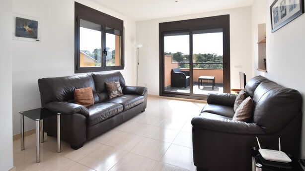 A spacious living area with two leather sofas, a small table, and a balcony with outdoor furniture. - Casa La Torreta (Begur) (Begur)