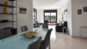 A modern living room with a glass dining table, leather sofas, and a balcony with a view. - Casa La Torreta (Begur) (Begur)