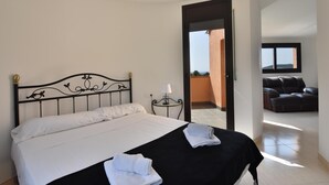 A bedroom with a bed, a nightstand, a lamp, a black leather sofa, and a view of the outside. - Casa La Torreta (Begur) (Begur)