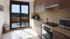 A modern kitchen with wooden cabinets, a built-in oven, and a large window overlooking a balcony. - Casa La Torreta (Begur) (Begur)