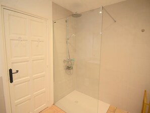 A bathroom with a glass shower enclosure, a white door, and a tiled floor. - Casa Els Pinetells (Begur) (Begur)