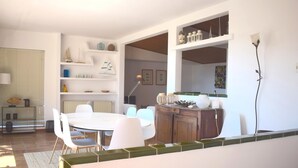 Una cocina moderna con comedor, muebles blancos y vistas al salón.